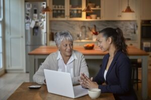 Financial advisor explaining paperwork to elderly retired woman in her kitchen